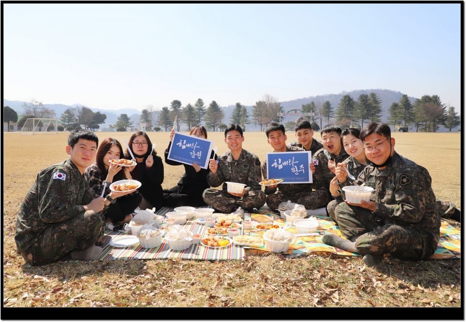 36사단 간부들이 지역상권을 돕기 위해 원주 대표시장인 중앙시장에서 가져온 음식을 먹으며 ’힘내라 강원, 힘내라 원주‘ 응원 팻말을 들어 보이고 있다
