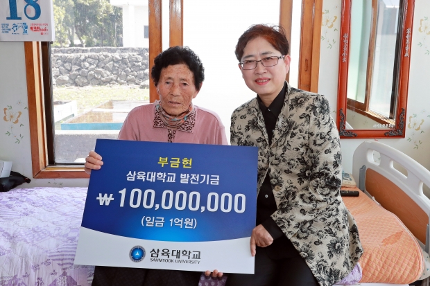 부금현 할머니(왼쪽)가 삼육대 김정숙 대외협력처장에게 대학 발전기금 1억원 전달 기념 사진을 찍고 있다. 장소는 할머니의 제주 자택