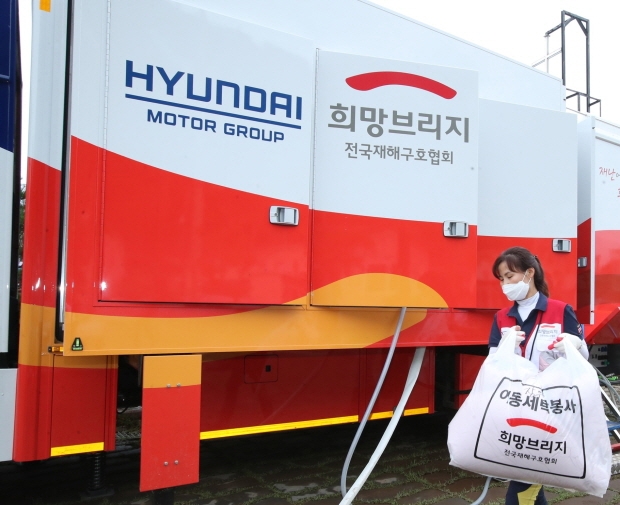 최근 폭우와 침수로 피해를 입은 경북 영덕군 강구면 강구시장에서 현대차그룹의 세탁구호차량과 함께 희망브리지 전국재해구호협회 자원봉사자들이 세탁 봉사활동을 하고 있는 모습(※ 사진 제공: 희망브리지 전국재해구호협회)