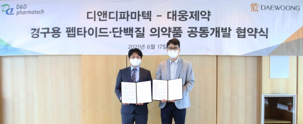 전승호 대웅제약 대표(오른쪽)와 임성묵 디앤디파마텍 대표가 협약서에 서명한 뒤 기념촬영을 하고 있다.