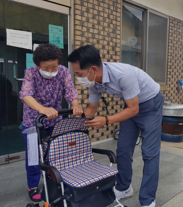 오동기 우성면장이 거동이 불편한 어르신에게 보행보조기를 전달하며 사용법을 자세히 알려드리고 있다