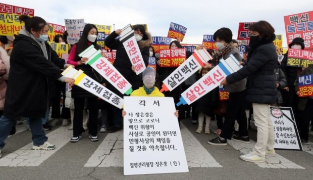 '강제접종' '무한접종' 등이 적힌 피켓을 들고 정은경 질병관리청장 가면을 쓴 사람에게 접종하는 퍼포먼스