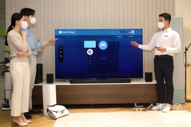서울 코엑스에서 열린 ‘월드IT쇼 2022’ 삼성전자관에 마련된 팀삼성 홈의 IoT리빙룸에서 관람객이 IoT허브가 탑재된 ‘Neo QLED 8K’로 별도 허브 없이도 스마트싱스를 이용해 다양한 가전과 기기를 컨트롤 해보고 있다. /사진 : 삼성전자