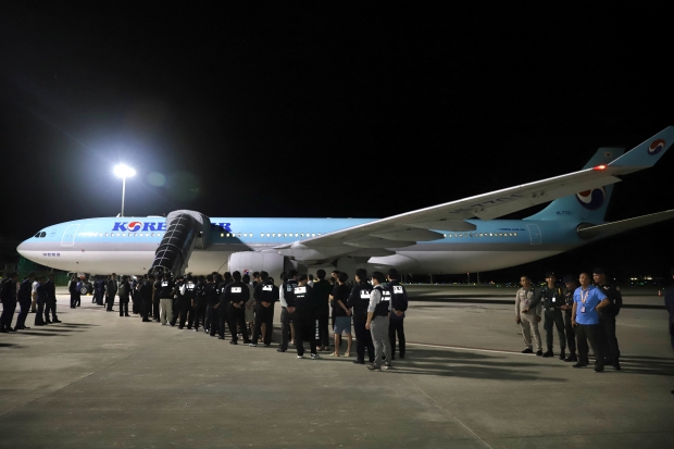 지난 18일, 캄보디아 캔달주 테초 국제공항에서, 온라인 사기 혐의를 받는 한국인들이 대한민국 경찰의 호송을 받으며 항공기에 탑승하고 있다. / 로이터 통신