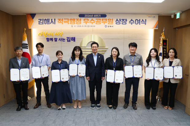 정영두 김해시장(가운데)이 28일 ‘2026년 상반기 적극행정 우수공무원’으로 선발된 공무원 9명에게 상장을 수여한 뒤 기념촬영을 하고 있다./사진=김해시
